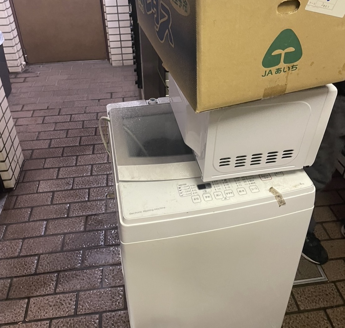 南区井土ケ谷下町での回収前｜アパートの外廊下に出した縦型洗濯機と電子レンジ、段ボール